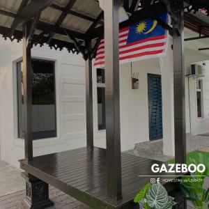 a house with an american flag on the porch at Homestey de Usraty in Kampung Sungai Baharu +1 photo