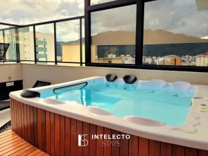 a jacuzzi tub in a room with windows at Apê 75 •Central, Jacuzzi, Academia, A/C, Vista Top in Poços de Caldas