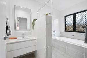 a white bathroom with a sink and a bath tub at The Crest North Harbour Estate Sleeps 8 in Burpengary East +12 photos