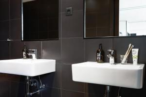 a bathroom with two white sinks and a mirror at The Social Hub Madrid Extended Stay in Madrid +28 photos