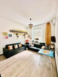 een woonkamer met een zwarte bank en een surfplank aan de muur bij surf house in Lido di Ostia