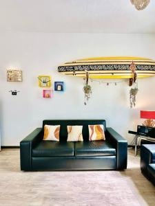 een zwarte bank in een kamer met een surfplank aan de muur bij surf house in Lido di Ostia