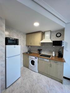 a kitchen with a white refrigerator and a washer at Atico en Tina Mayor in Unquera +10 photos