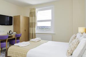 a hotel room with a bed and a desk and a window at Majestic Hotel Eastbourne by Belvilla in Eastbourne