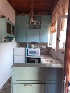 a small kitchen with blue cabinets and a microwave at Poline s House With Garden & Sea In Zero Distance in Kakongiónion