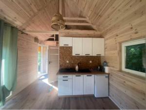 a kitchen with white cabinets and a wooden ceiling at Trzy sosny in Supraśl