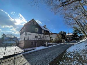a house with a fence on a snowy street at Willa Anna in Szczawno-Zdrój