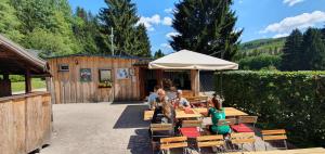 un grupo de personas sentadas en mesas bajo un paraguas en Naturcamp Meyersgrund - Campingplatz, en Manebach