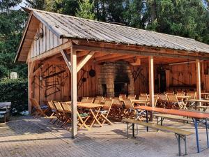 un pabellón de madera con mesas, sillas y chimenea en Naturcamp Meyersgrund - Campingplatz, en Manebach