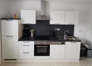 a kitchen with white cabinets and a sink at Ferienwohnung Schickling in Großenlüder