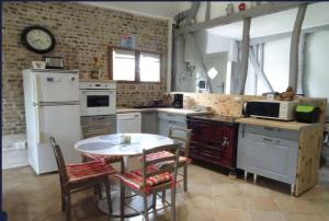 a kitchen with a table and a white refrigerator at Le Nid de Boismont in Boismont