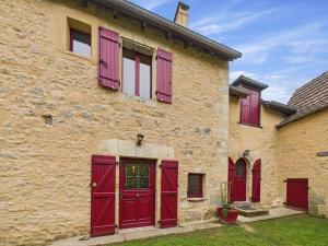 un bâtiment en briques avec des portes et des fenêtres rouges dans l'établissement Charmante maison en pierre pour 6 - Valojoulx, à Castang