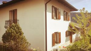 a white building with brown windows and a tree at Apartma Pri noni Silvi in Tolmin