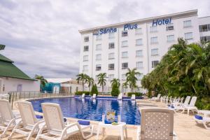 a hotel with a pool and chairs and a building at Sanha Plus Hotel in Santa Marta