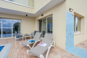 a patio with two chairs and a swimming pool at H&O Miki's Seaview House in Kissonerga +58 photos