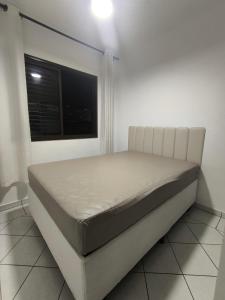 a white bed in a room with a window at Residêncial frente praia - Mirim - Praia Grande in Praia Grande