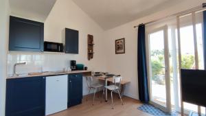 a kitchen with blue cabinets and a table with chairs at Chez Marion et Sylvain in Saint-Hilaire-de-Chaléons