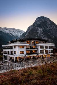ein Hotelgebäude mit Bergen im Hintergrund in der Unterkunft Arthur's Hotel und Apartments am Achensee in Maurach