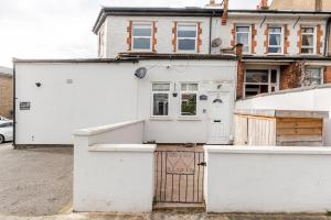 a white house with a gate in front of it at Spacious 2 BED 2 BATH Apartment with FREE PARKING for 2 cars and underground station Zone 2 for quick access to Central London up to 10 guests in London