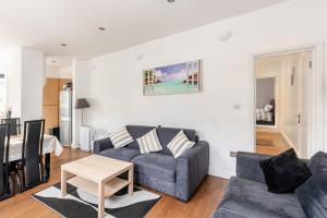 a living room with a couch and a table at Spacious 2 BED 2 BATH Apartment with FREE PARKING for 2 cars and underground station Zone 2 for quick access to Central London up to 10 guests in London