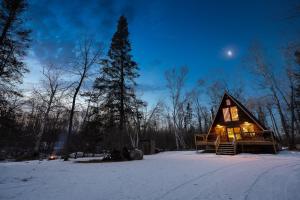a cabin in the woods in the snow at night at River End A-Frame in Emily