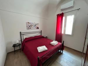 a bedroom with a red bed with two towels on it at Appartamento Il Dammuso in Marsala