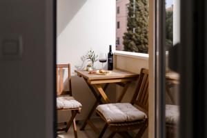 a small table and chairs on a balcony with a window at Olea Delux Rooms in Zadar