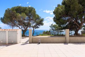 a fence with trees and the ocean in the background at Rentalmar Los Angeles in Miami Platja