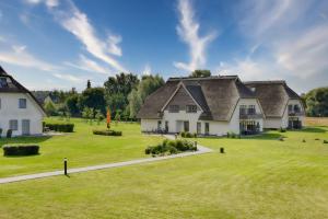 a large white house with a grass yard at Ferienwohnung Waldkauz 23 im Wreecher Idyll Rügen by ruyastay in Putbus