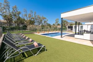 a group of lawn chairs sitting next to a swimming pool at Beach Villa Cosins 1 Mel by Sealand Villas in Alcudia