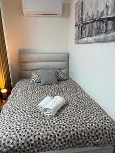 ein Bett mit einer schwarz-weißen Bettdecke und zwei Handtüchern in der Unterkunft Apartman ZEN 2 in Popovača