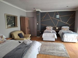 a bedroom with two beds and a chair at Retro Guesthouse in Vanderbijlpark
