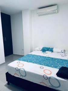 a bedroom with a bed with a blue and white blanket at Hermoso apartamento con Aire Acondicionado Cerca al Hospital de Neiva in Neiva