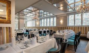 a room with white tables and chairs and windows at Thon Hotel Slottsparken in Oslo
