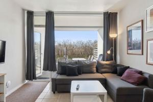Una sala de estar con un sofá y una ventana grande. en Holiday Apartment Near Bønnerup, en Glesborg