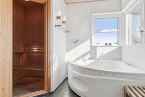 a white bathroom with a tub and a window at Holiday Dream On The West Coast in Brovst +28 photos