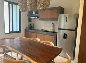 eine Küche mit Holztisch und Kühlschrank in der Unterkunft Tulum groups home for 7 guest with 2 bedrooms Balcony Common Pool Gym Yoga and mini Market Ximbal in Tulum