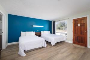 une chambre avec deux lits et un mur bleu dans l'établissement Lions Head Beach Motel & Cottages - WATERFRONT, à Lion's Head