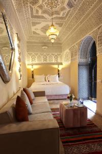 a bedroom with a bed and a couch and a table at Riad Atlas Dama in Marrakech +37 photos