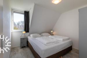 アーフテーケルケにあるGezellige 6-persoons vakantiewoning vlakbij het strand in Domburg op Ponyhof Aagtekerkeの白いシーツと窓のあるベッドのある寝室