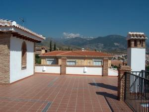 a house with a brick patio with mountains in the background at Hotel Los Rebites in Huétor Vega