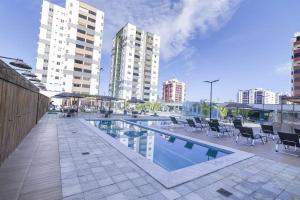 a swimming pool with chairs and tables and buildings at Apartamentos Aquarius Flat in Caldas Novas