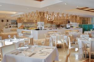 a restaurant with white tables and chairs and a kitchen at Hotel Jardín Tecina in Playa de Santiago