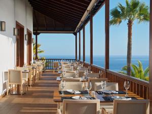 a restaurant with tables and chairs with the ocean in the background at Hotel Jardín Tecina in Playa de Santiago