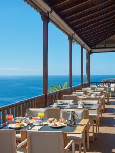 a row of tables and chairs on a balcony with the ocean at Hotel Jardín Tecina in Playa de Santiago