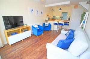 a living room with a white couch and blue chairs at Dros Y Dwr in Porthmadog
