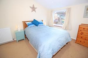 a bedroom with a blue bed and a window at Dros Y Dwr in Porthmadog