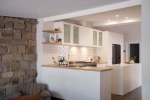 a kitchen with white cabinets and a stone wall at Traveller's Return Retreat in Fremantle