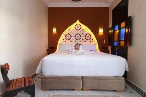 a bedroom with a large white bed with an ornate headboard at Riad Atlas Dama in Marrakech