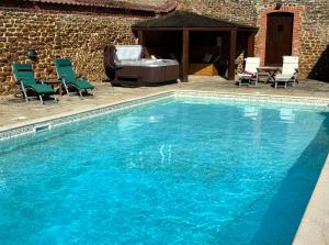 a large blue swimming pool with chairs and a tub at The Homemead in Heacham